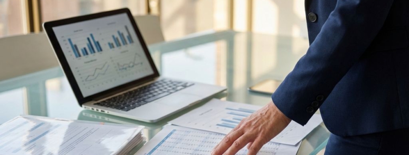 Professionele zakenvrouw in marineblauw pak analyseert financiële rapporten en grafieken op glazen vergadertafel