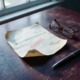 Vervallen factuur met rood stempel op verouderd houten bureau, leesbril en pen ernaast, zacht zijdelings licht.