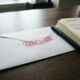 Witte envelop met rood DISPUTED-stempel op donker eiken bureau naast papieren factuur en zwarte pen.