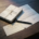 Stapel facturen, ondertekend contract en betalingsherinnering op donker eiken bureau met zwarte pen, bovenaanzicht.