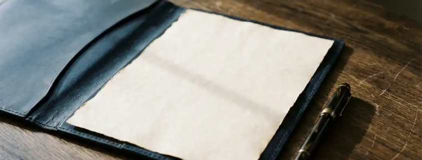 Opengevouwen leren contractmap op donker eiken bureau met ongetekende pagina en fonteinpen, zacht natuurlijk raamlicht.
