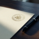 Officieel registratiecertificaat op eiken bureau met overheidszegel op crèmepapier en zwarte pen ernaast.
