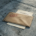 Bruin envelop met rood "return to sender"-stempel op betonnen ondergrond, gedeeltelijk zichtbare achterstallige factuur eronder.