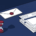Witte envelop met rood lakzegel naast gestapelde facturen en zandloper op bureau, illustratie in marineblauw en rood.
